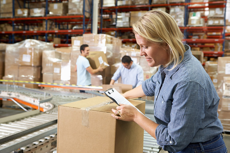 Woman looking at a clipboard at a package distribution center